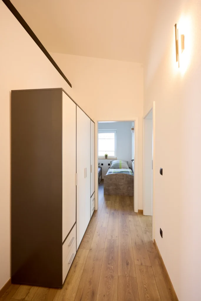 Flur mit großem Kleiderschrank und Blick in das Zimmer mit Einzelbetten