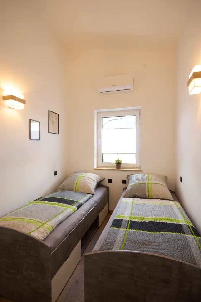 Zweites Schlafzimmer mit zwei Einzelbetten, Fenster und Klimaanlage